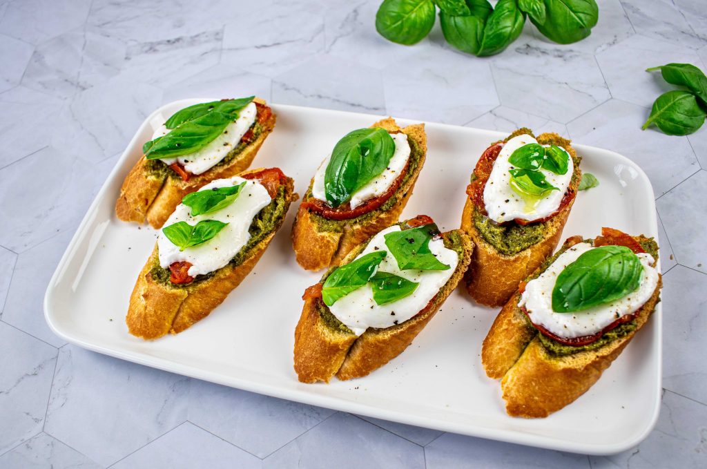 Brusketos su pesto, pomidorais ir mocarela. Patiekta
