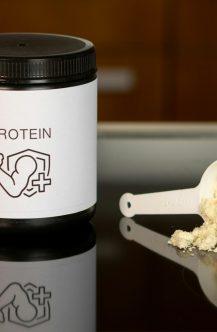 a container of protein powder next to a spoon