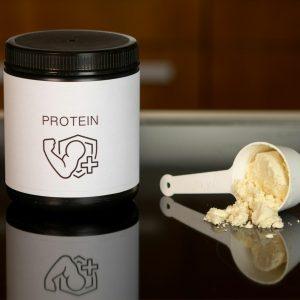 a container of protein powder next to a spoon