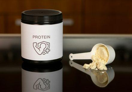 a container of protein powder next to a spoon